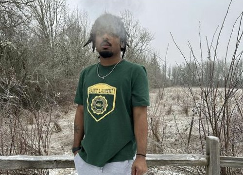 Izaya standing outside on a cold snowy day with a green t-shirt