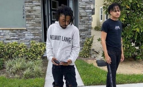 Izaya standing outside wearing a hoodie with fellow rapper Summrs